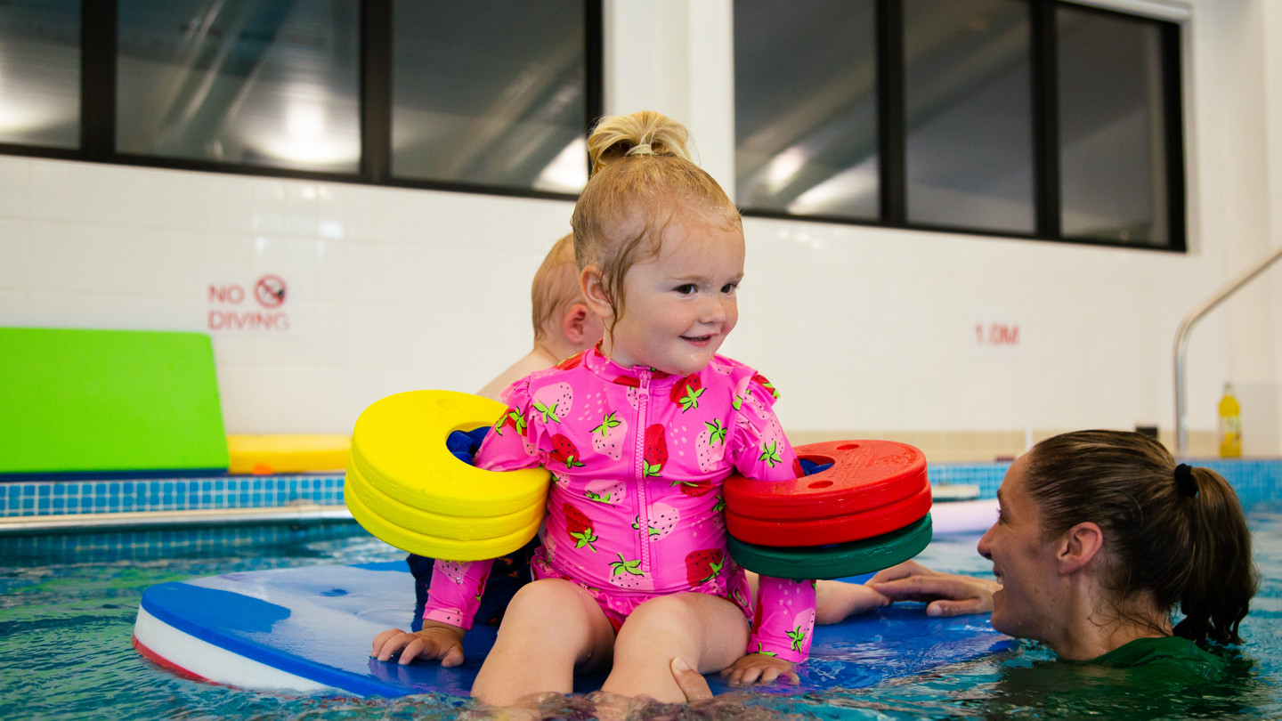 Kids sitting on float in swimming lessons