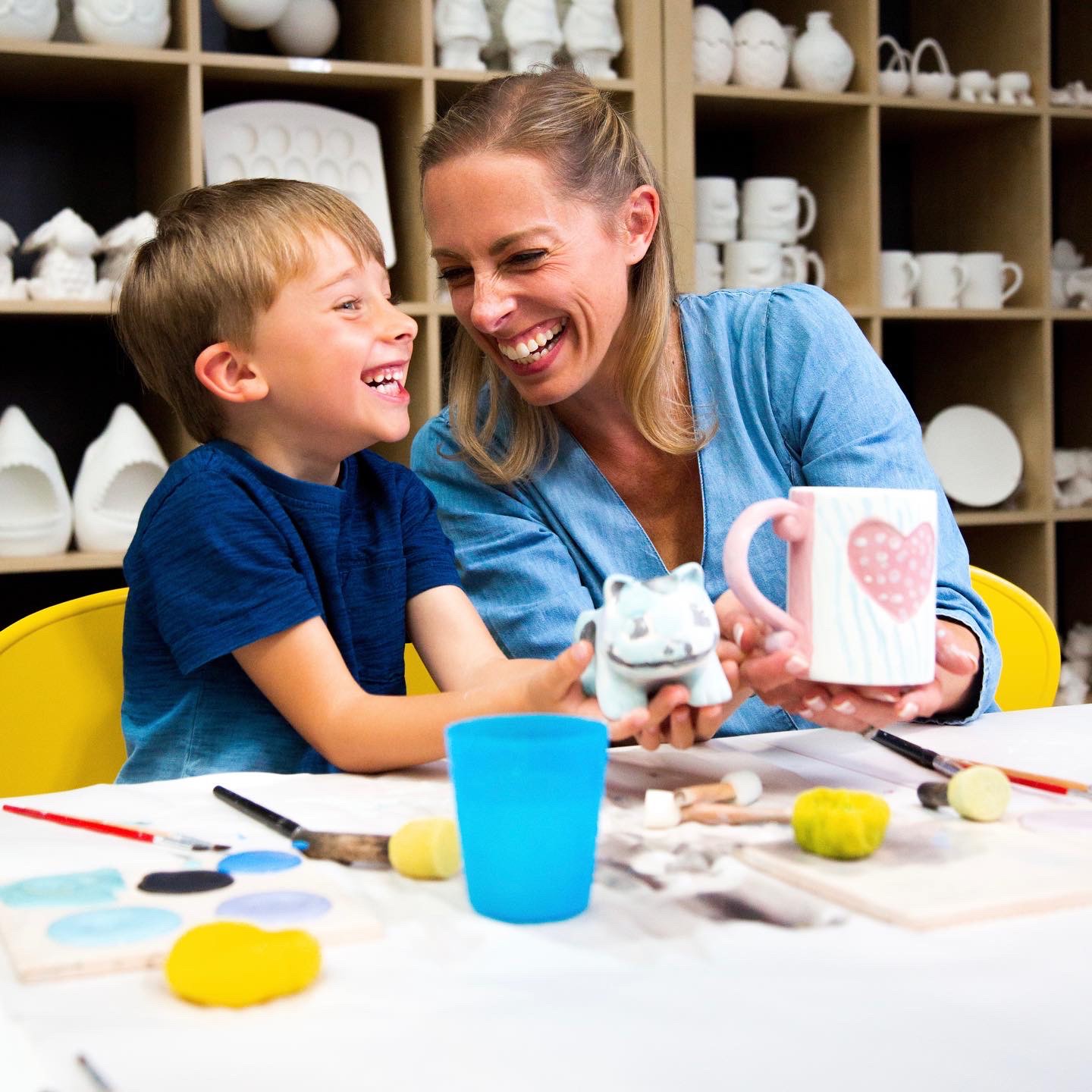 Child and parent painting clay mugs