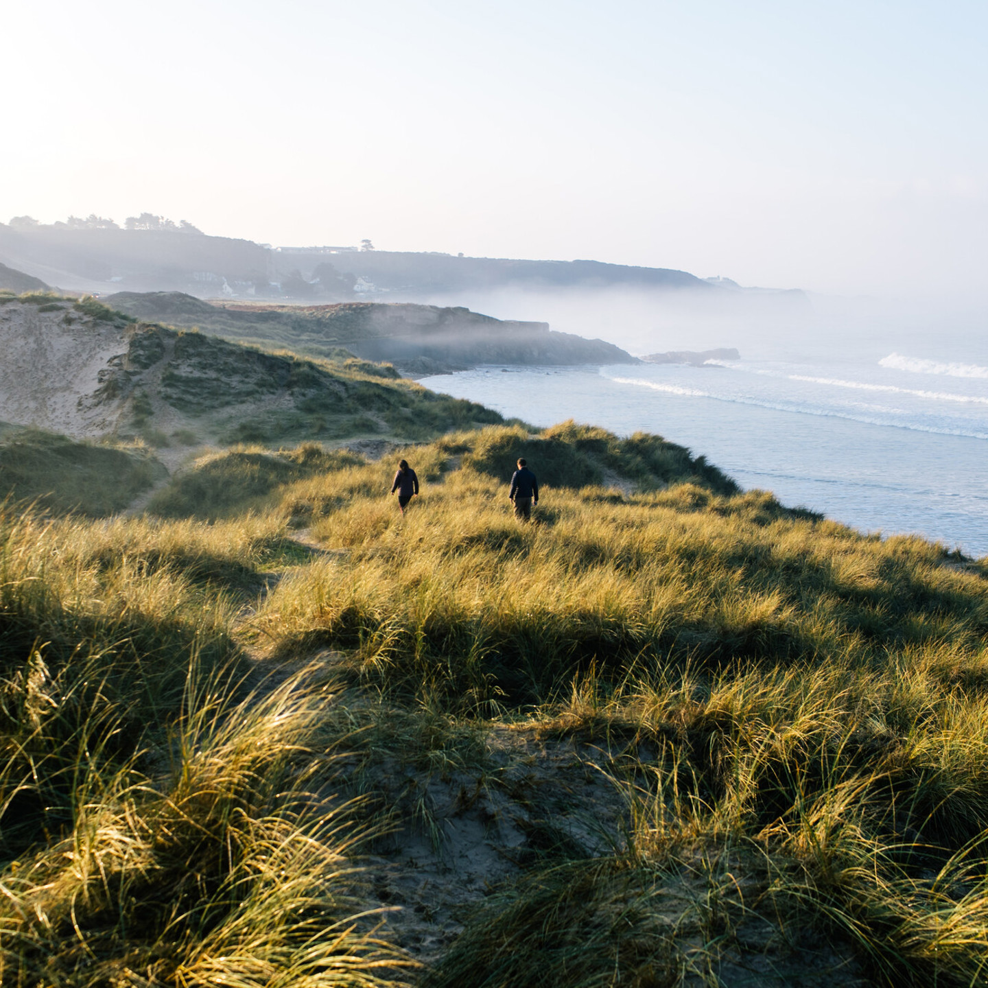 Couple walking along the coast of the sand dunes